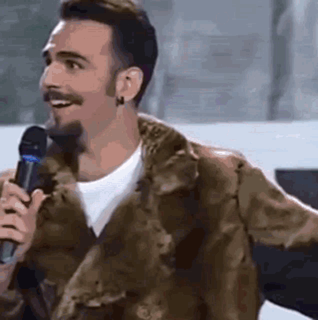 a man is holding a microphone and smiling .