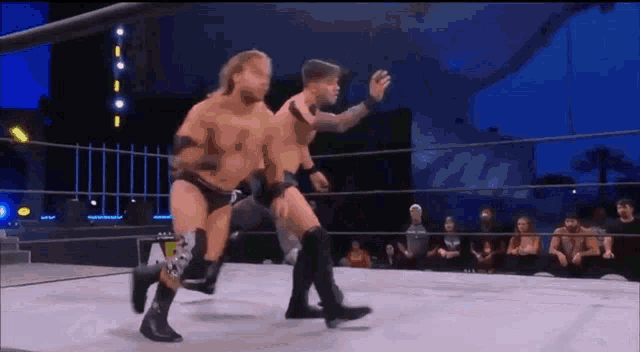 two wrestlers are fighting in a wrestling ring .