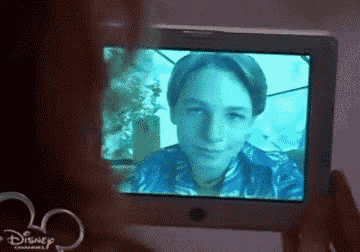 a person is taking a picture of a young boy on a disney television screen .