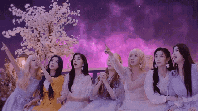 a group of women are sitting in front of a purple background