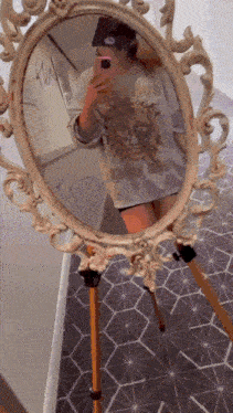 a woman is taking a selfie in front of a mirror with a sun on her shirt