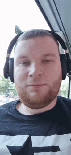 a man with a beard wearing headphones and a shirt that says t on it