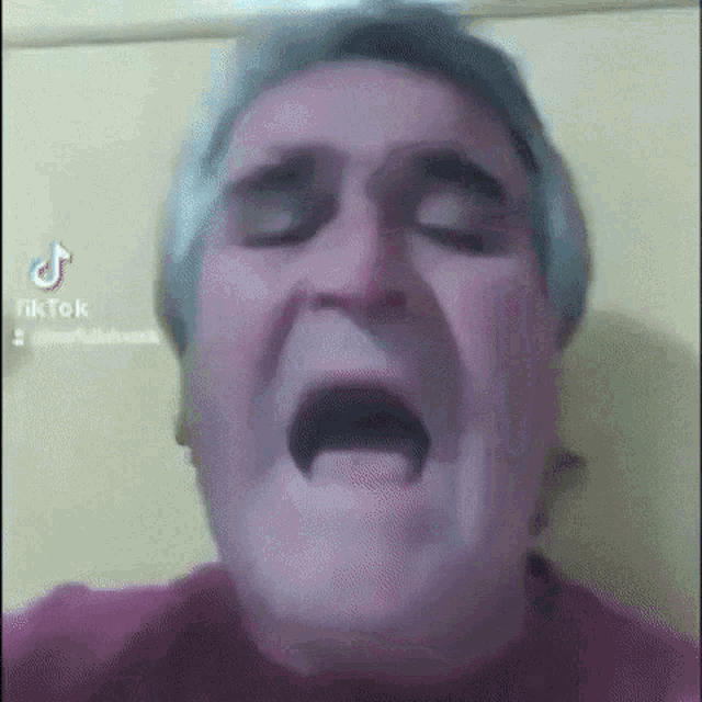 a man with gray hair is making a funny face with his mouth open and his eyes closed .