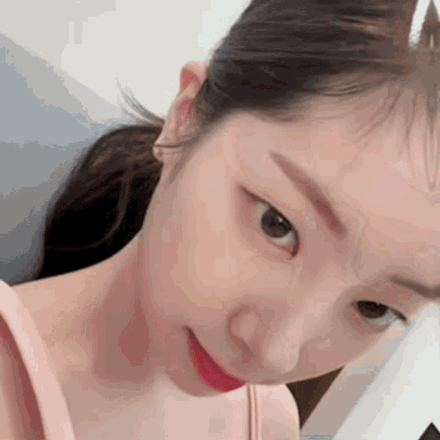 a close up of a woman 's face with a pink tank top
