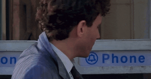 a man standing in front of a phone booth that says phone