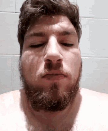 a shirtless man with a beard is making a funny face
