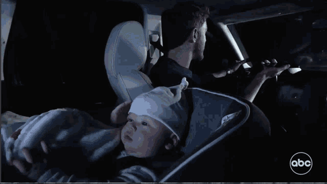a baby is sitting in a car seat with abc written on the bottom right