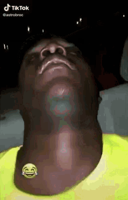 a man with a smiley face on his neck is looking down .