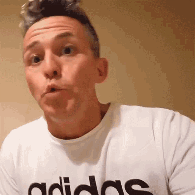 a man wearing an adidas t-shirt makes a funny face