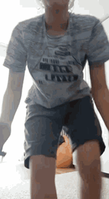 a young boy wearing a t-shirt and shorts is standing on one leg .