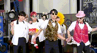 a group of young men dressed in costumes are standing next to each other in front of a stage .