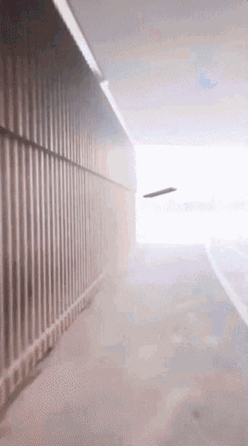 a plane is flying through a tunnel with a wooden fence in the background