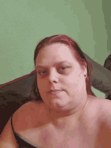a woman with red hair is laying on a bed looking at the camera