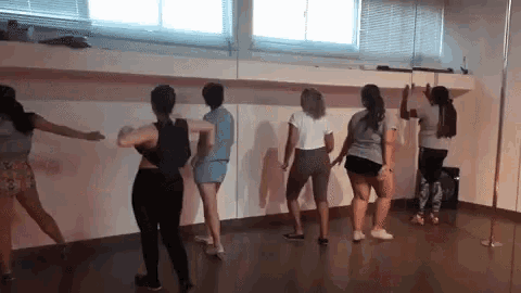 a group of women are standing in a dance studio dancing .