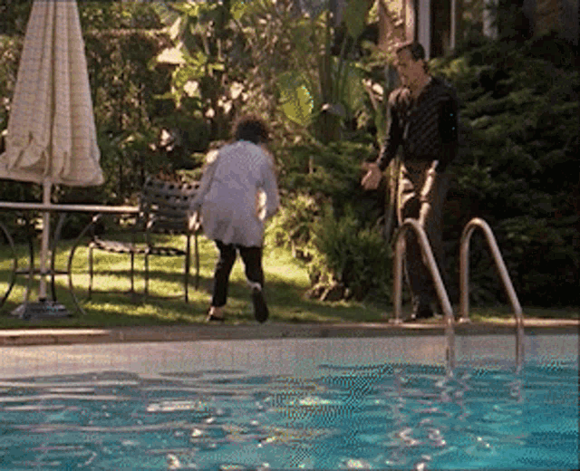 a man is standing next to a swimming pool