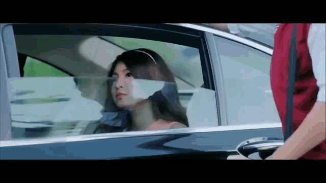 a woman is looking out the window of a car