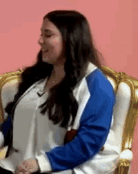 a woman in a blue and white jacket is sitting on a chair