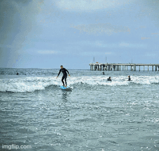 a group of people standing in the water holding surfboards with the watermark imgflip.com