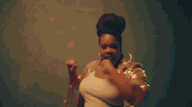 a woman with a bun on her head is wearing hoop earrings and a sequined jacket