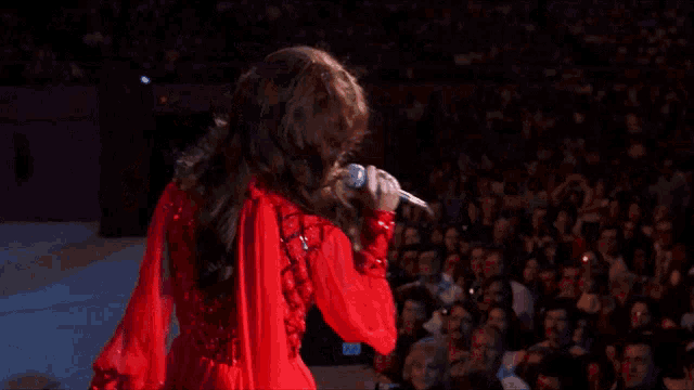 a woman in a red dress is singing into a microphone