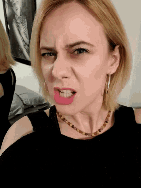 a woman wearing a necklace and hoop earrings is making a funny face