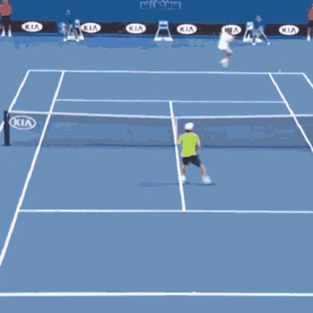 a man in a green shirt is playing tennis on a kia sponsored court