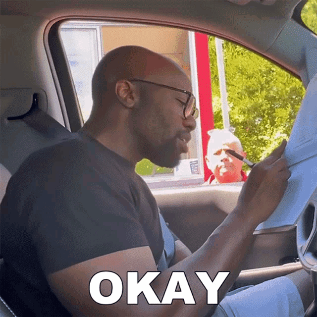 a man in a car with okay written on the bottom