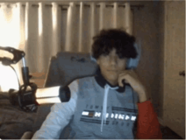 a young man wearing headphones and a tommy hilfiger sweatshirt