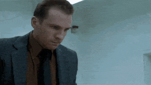 a man in a suit and tie is looking down at something .