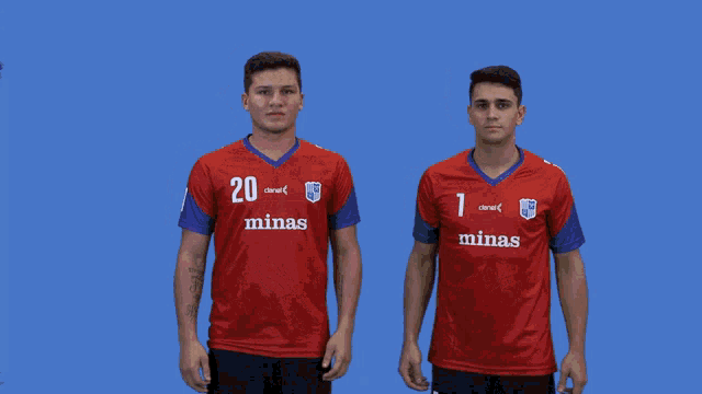 two men wearing red minas jerseys stand next to each other on a blue background