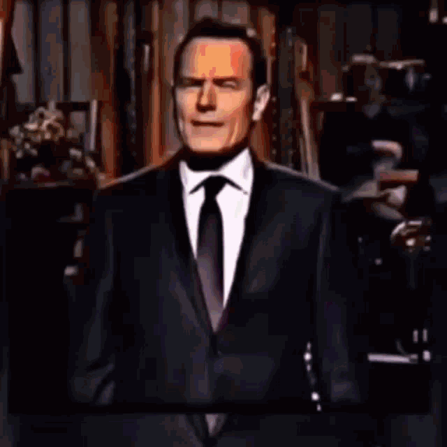 a man in a suit and tie is holding a microphone and talking into it .