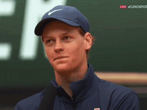 a man wearing a blue nike hat stands in front of a sign that says eurosport