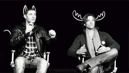 a black and white photo of two men sitting next to each other in chairs .