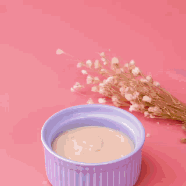 a bowl of strawberries sits next to a bowl of cream