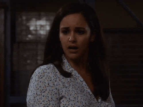 a woman with a surprised look on her face wearing a floral shirt