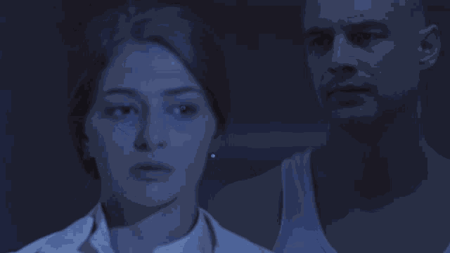 a man and a woman are standing in a window at night