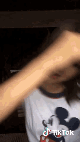 a woman wearing a mickey mouse shirt is making a tik tok video