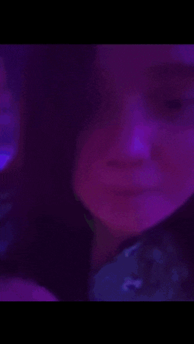 a close up of a girl 's face with purple and blue lights in the background