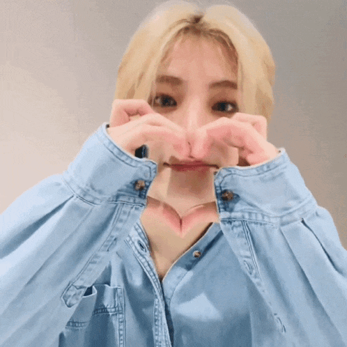 a woman making a heart with her hands in front of her face