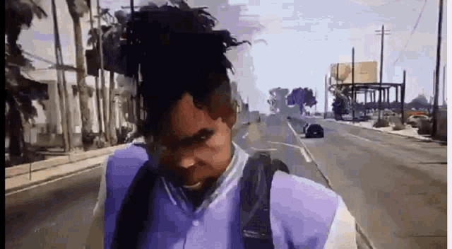 a man in a purple jacket is walking down a street in a video game .