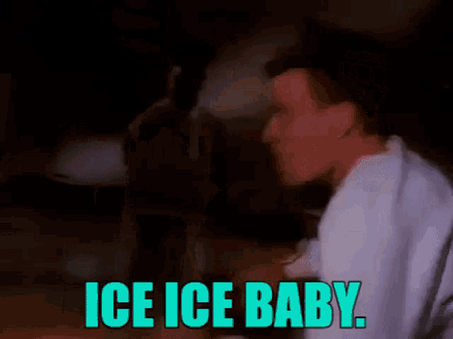 a man in a white shirt is dancing in a dark room with the words `` ice ice baby '' written on it .