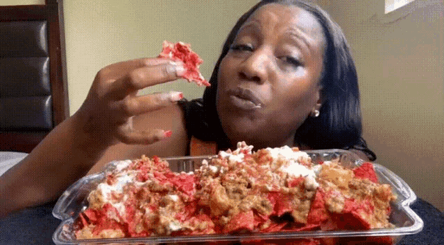 a woman is eating a container of nachos with a slice missing