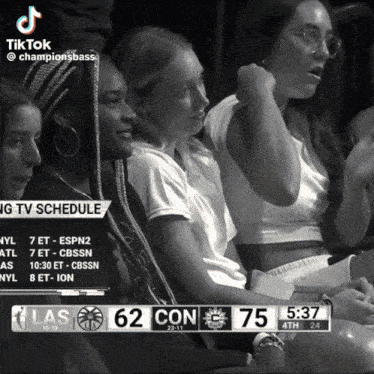 a black and white photo of people watching a game with the score 62 to 75