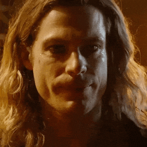 a close up of a man with long blonde hair