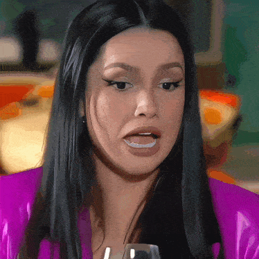 a woman with long black hair is wearing a purple jacket and holding a glass