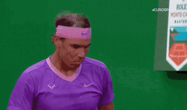 a man wearing a purple shirt and a pink headband looks down