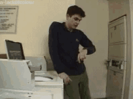 a man standing in front of a washer and dryer looking at his wrist watch