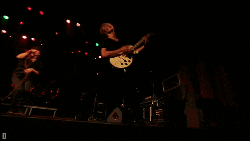 a man singing into a microphone and another man playing a guitar on stage