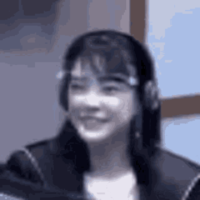 a woman wearing headphones and glasses is smiling .