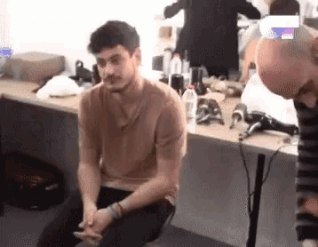 a man is sitting on a chair in front of a table with a hair dryer .